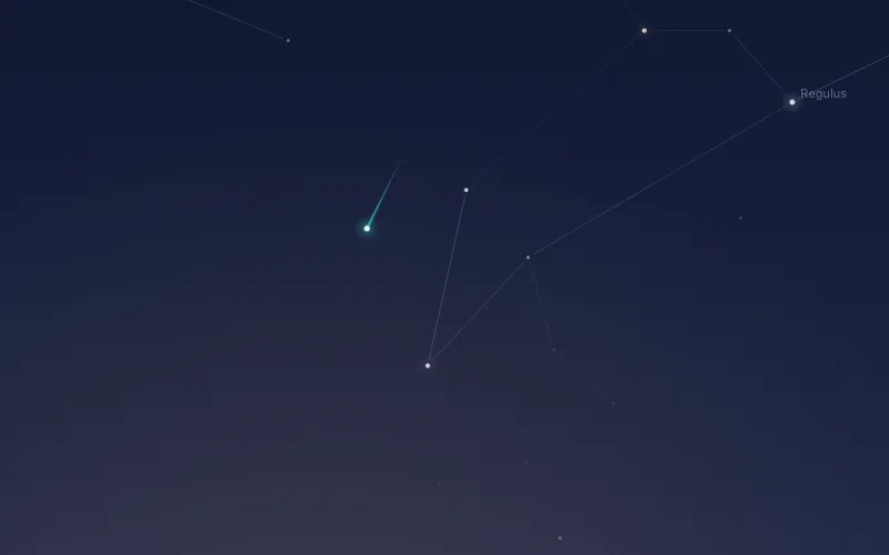 Close-up of a small white point in a cyan glow with a thin cyan trail fading up and to the right, beside faint constellation lines and a star labelled Regulus, on a dark blue sky that lightens towards the bottom.